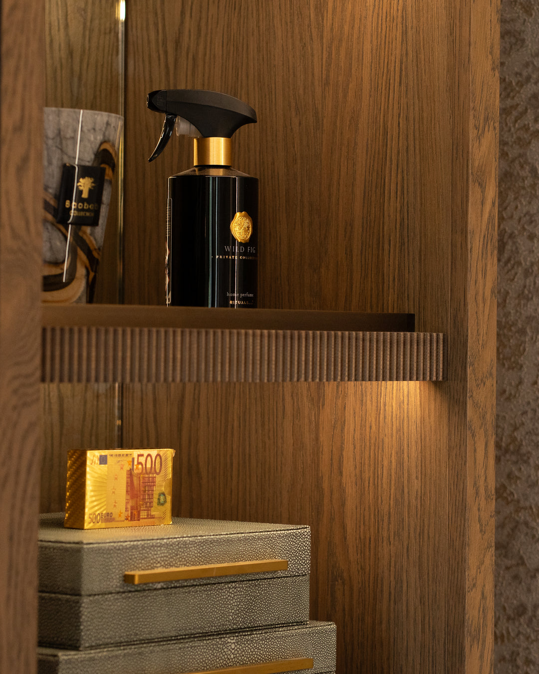 Black spray bottle with gold accents on a wooden shelf