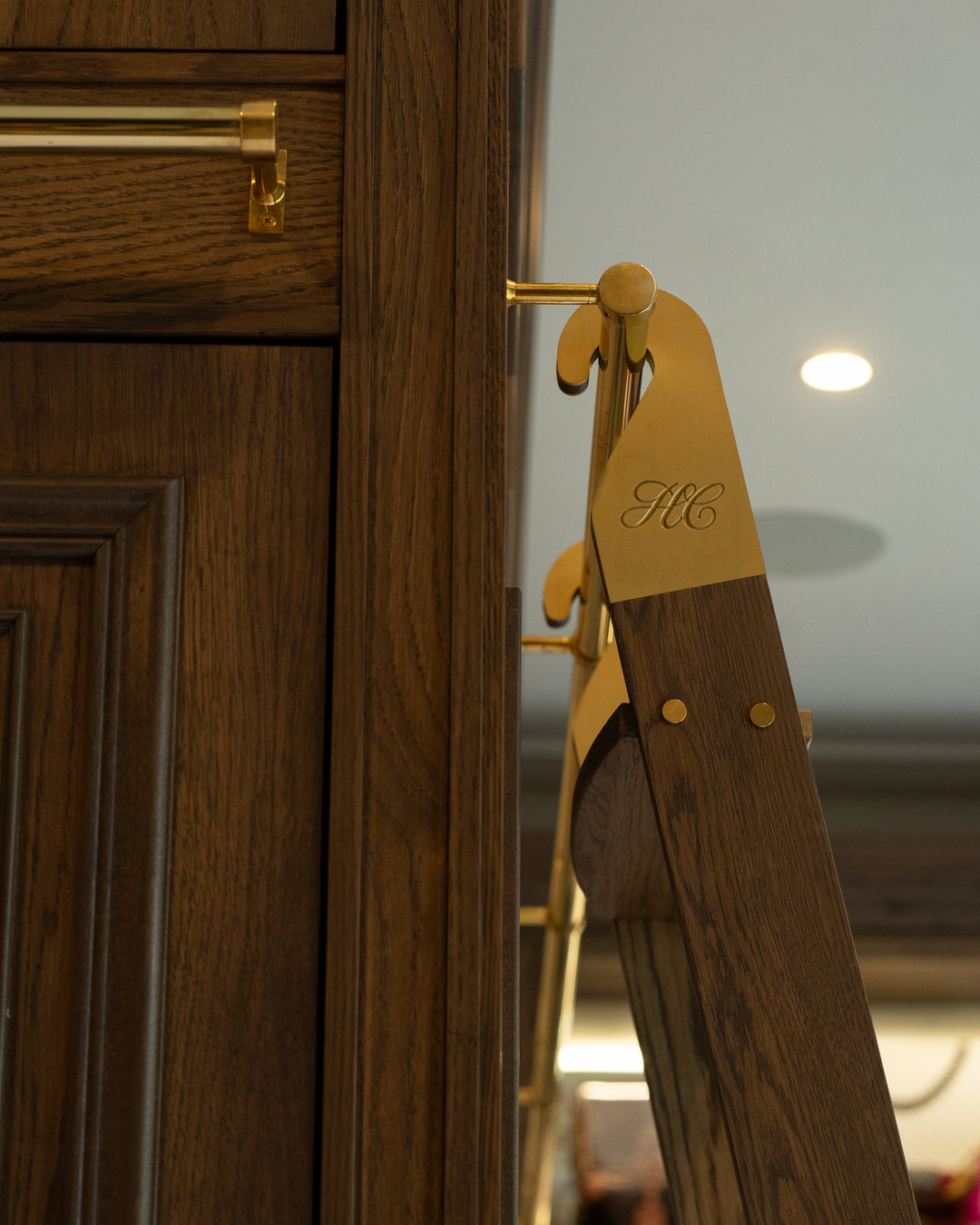Wooden ladder with gold handle and 'HC' engraving, blurred background