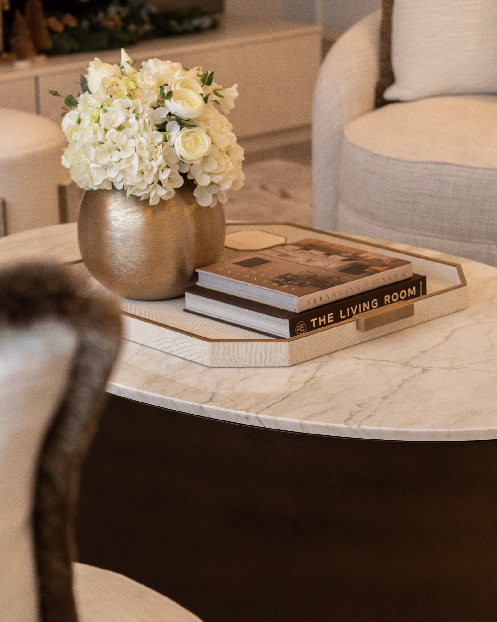 Marble coffee table styled with books and floral arrangement in a luxury living space.