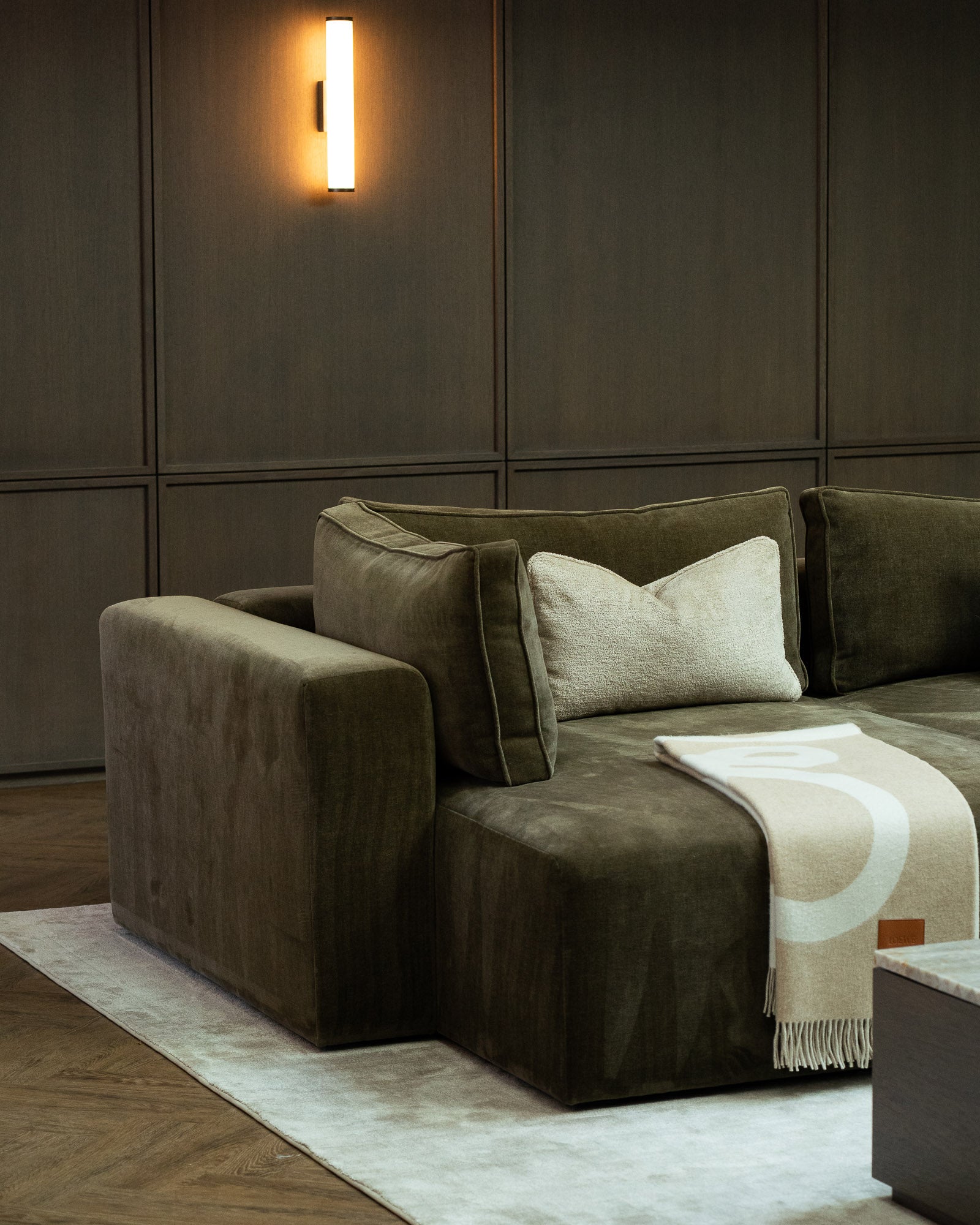 Bespoke sectional sofa set against dark wall panelling in a luxury media room.