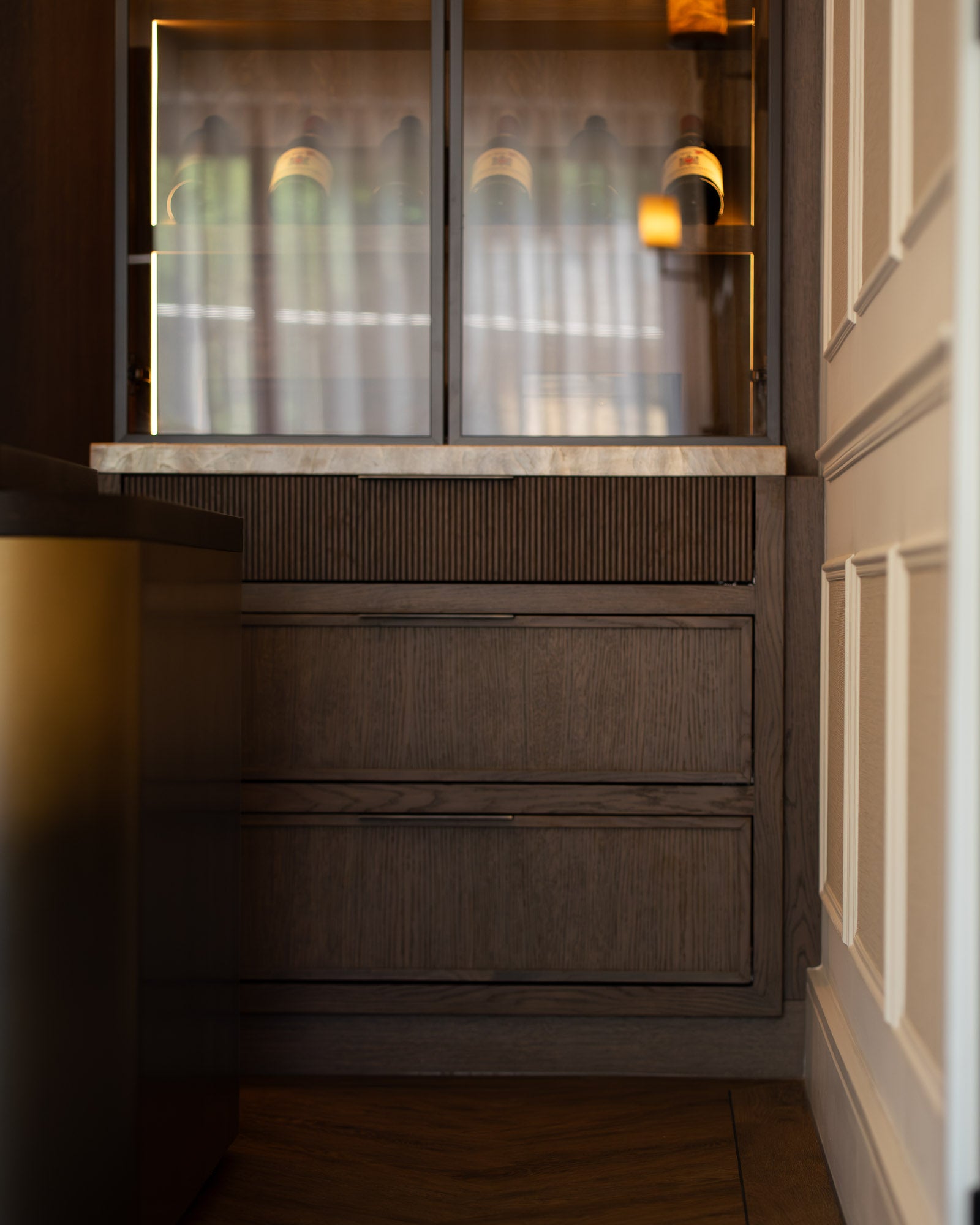Bespoke oak cabinetry with integrated wine display and marble worktop.