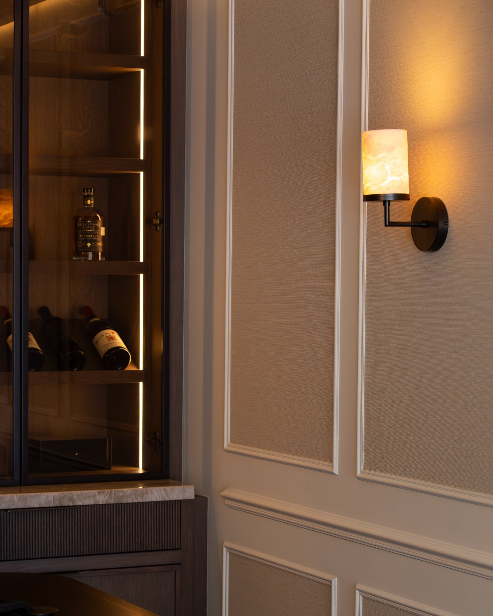 Illuminated wine display cabinet with marble worktop and feature wall lighting.