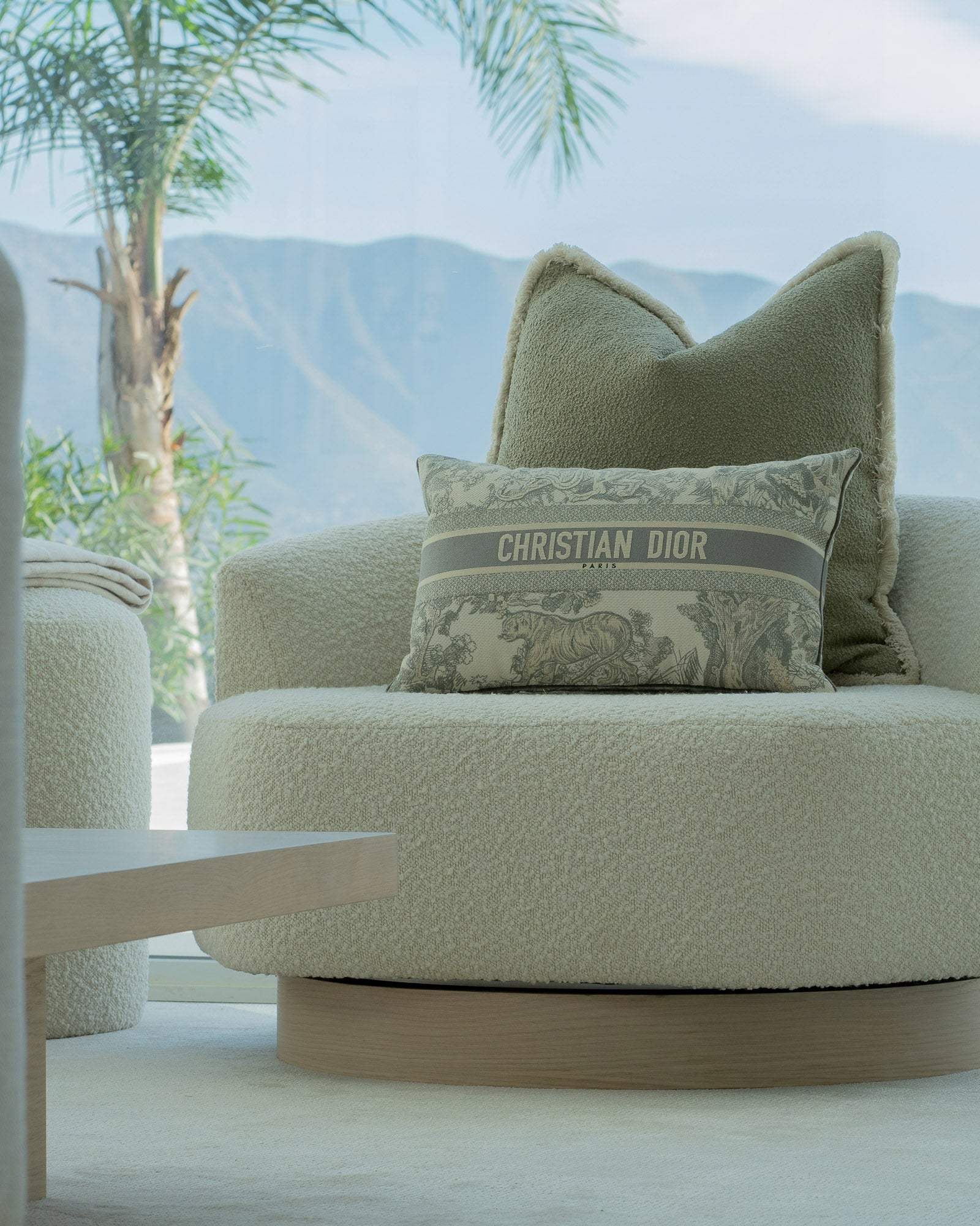 Curved lounge chair with Dior cushion overlooking mountain views.