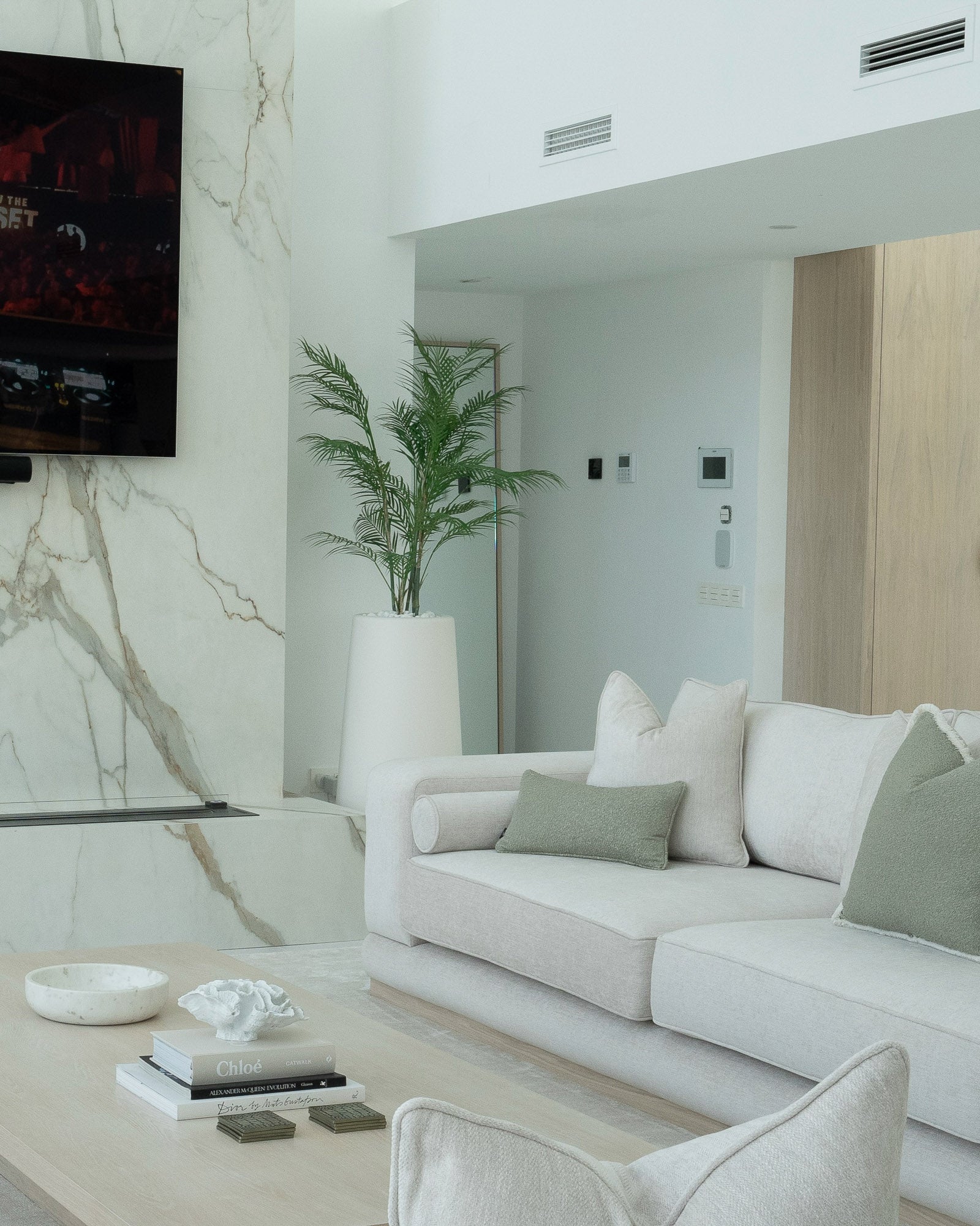 Luxury living room featuring marble feature wall, bespoke joinery and contemporary furnishings.