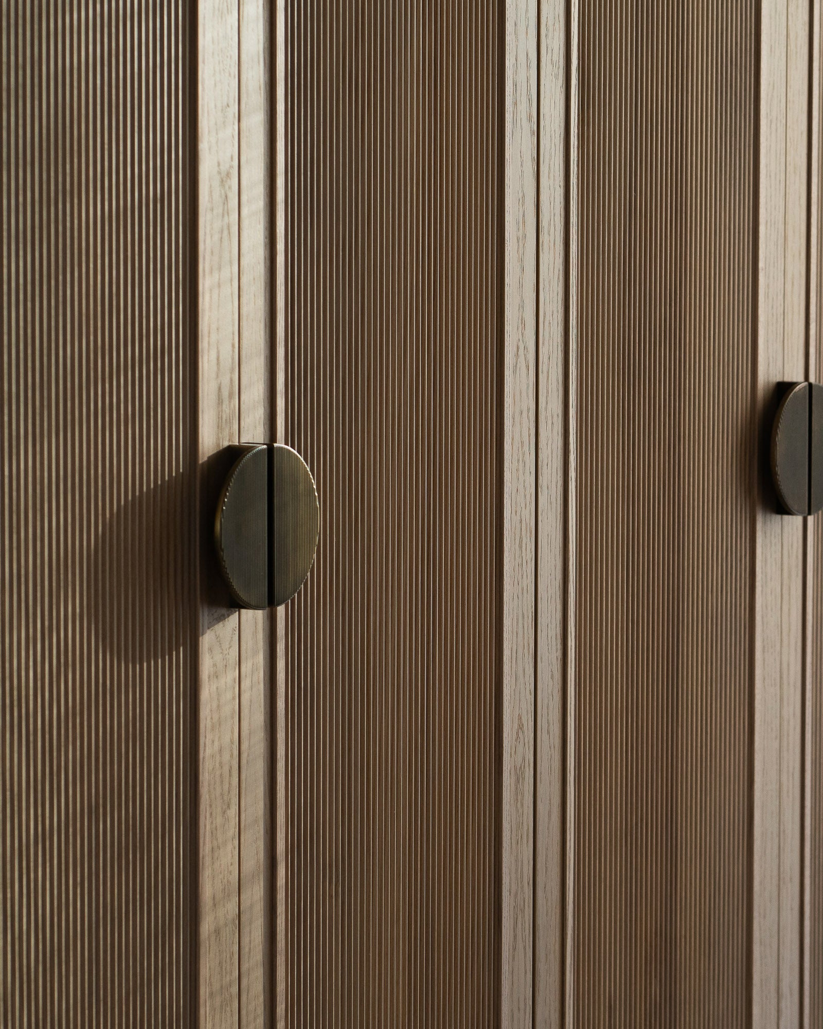 Fluted oak wardrobe doors with bespoke bronze handles.