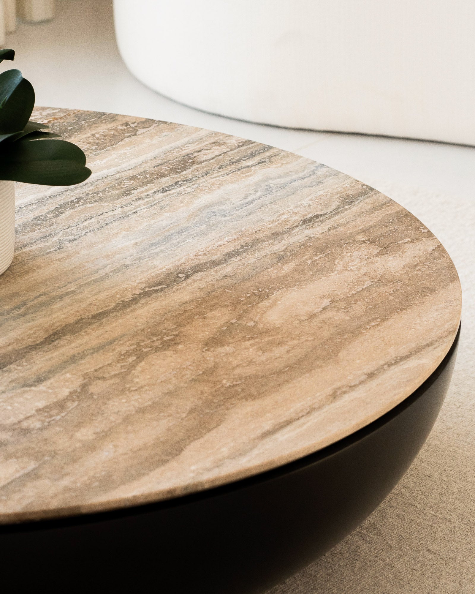 Round stone coffee table with sculptural base in a luxury living room.