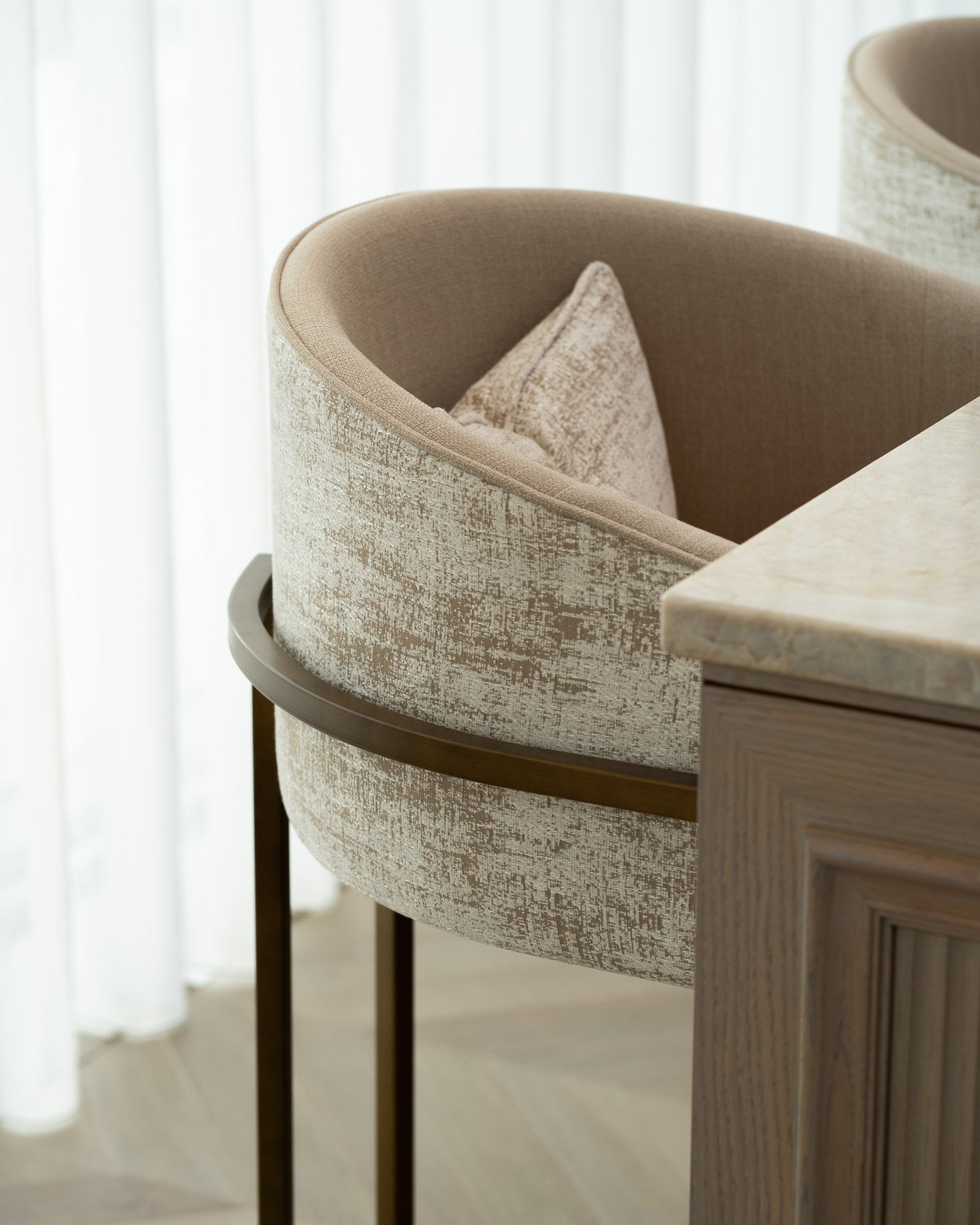 Bespoke upholstered dining chair beside a fluted oak island unit in a luxury interior.