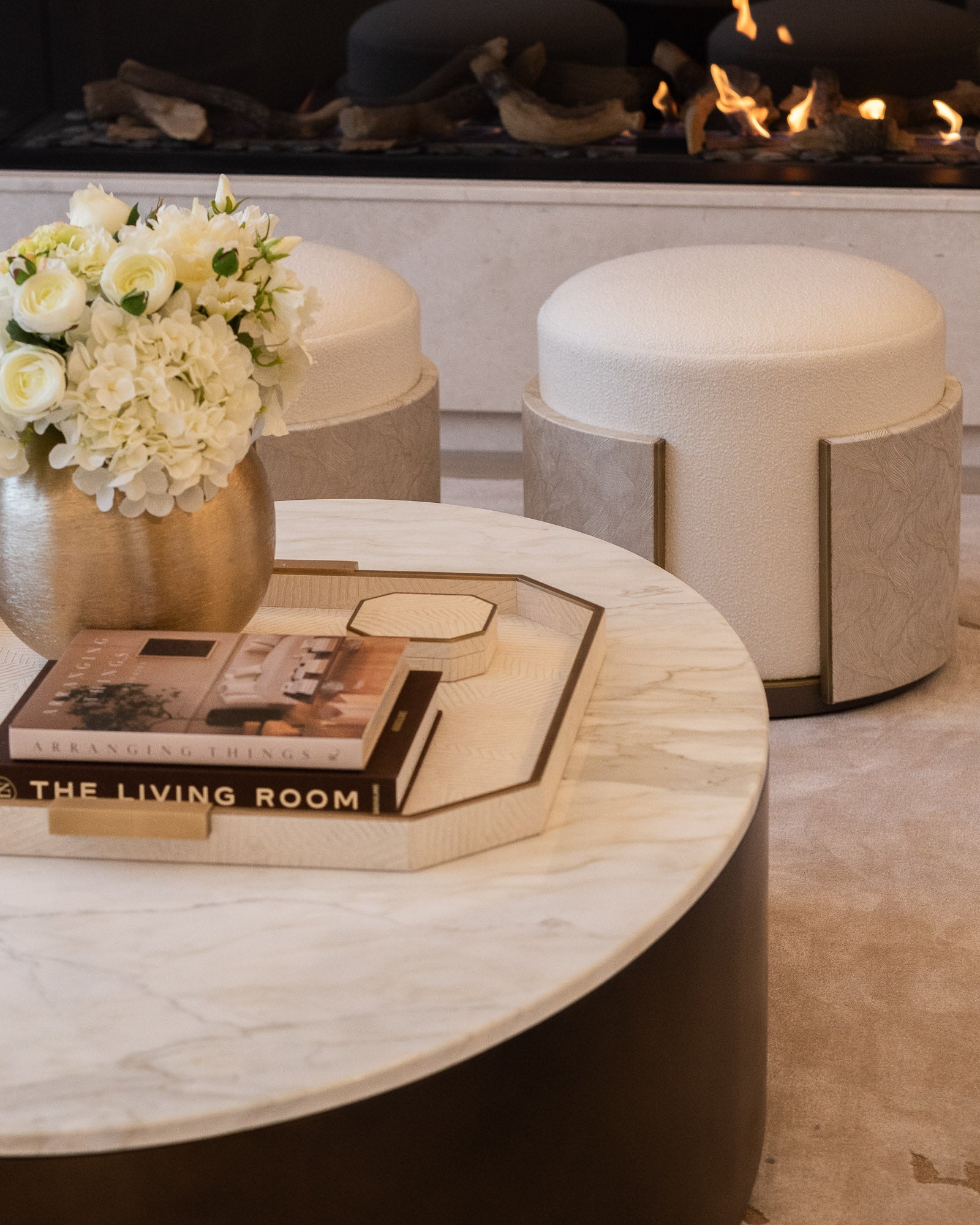 Marble coffee table styled with books and floral arrangement in a luxury living room.