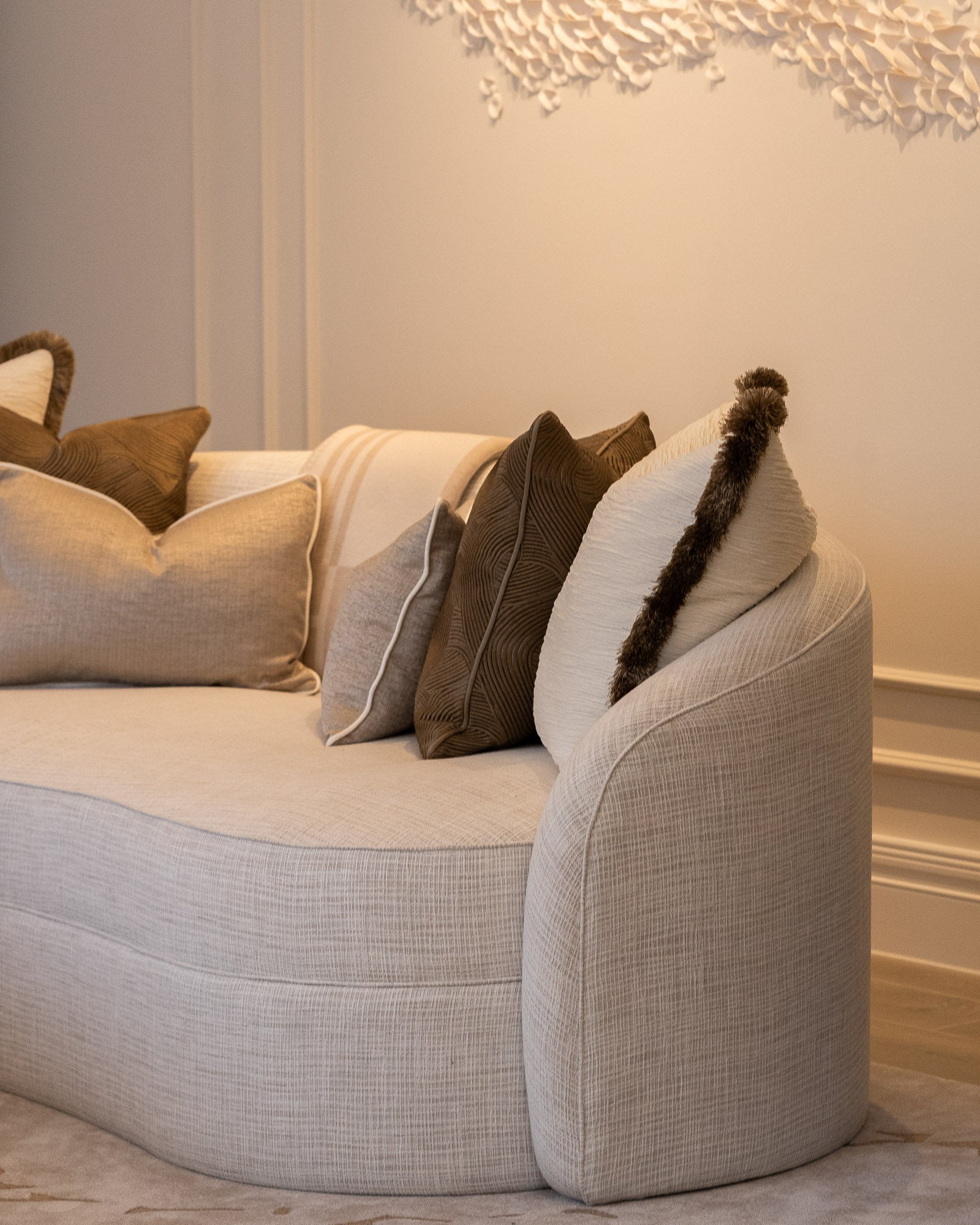 Curved upholstered sofa with layered cushions in a luxury living room.