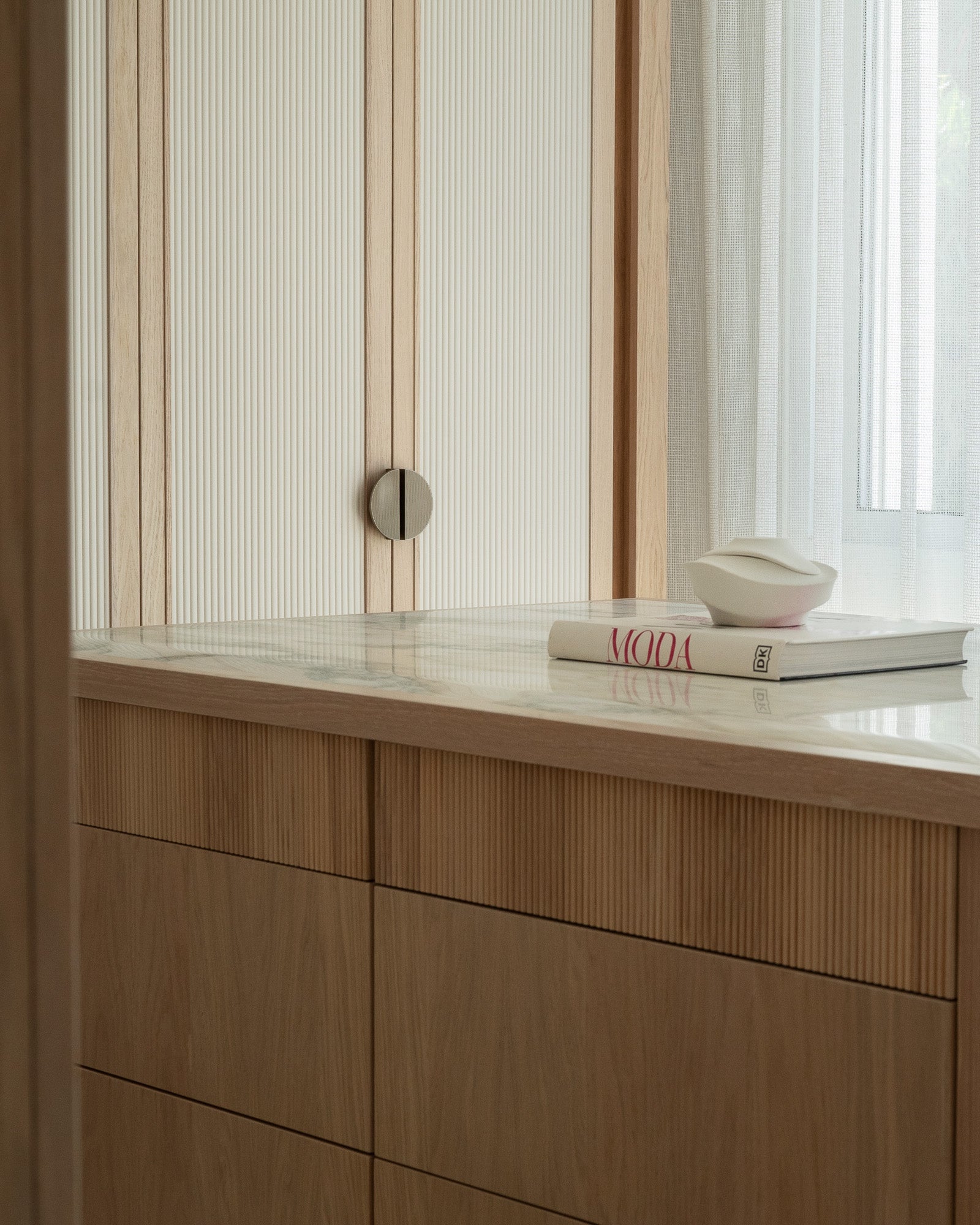 Bespoke oak vanity with integrated storage and sheer window treatments.