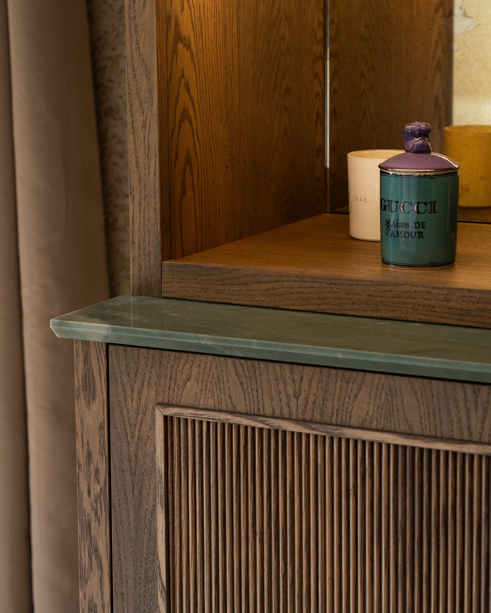 Detail of bespoke walnut cabinetry with green stone surface and decorative accessories