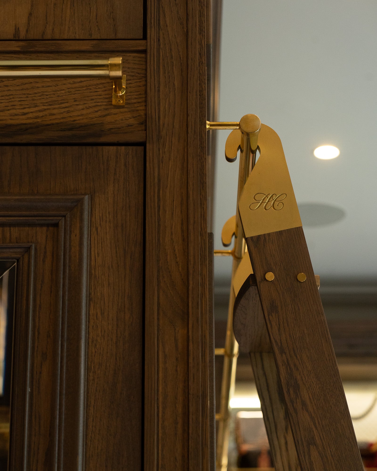 Detail of bespoke walnut dressing room joinery with aged brass ladder hardware