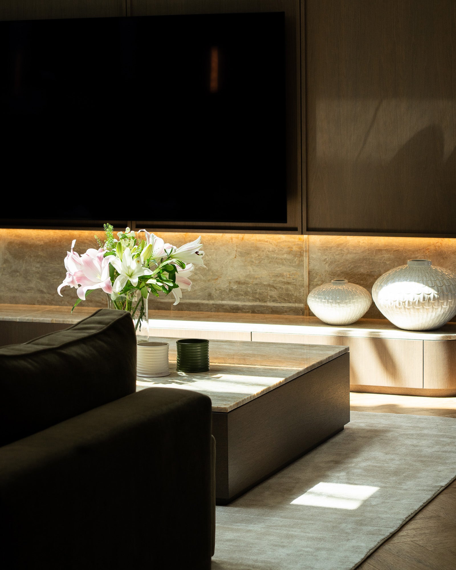 Contemporary living room with bespoke media wall and stone coffee table at The Sevenoaks Residence